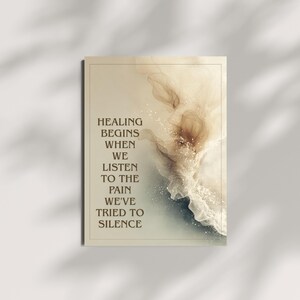 May include: A framed art print with the text "HEALING BEGINS WHEN WE LISTEN TO THE PAIN WE'VE TRIED TO SILENCE." The artwork features a soft, abstract design in shades of beige, brown, and white, with a subtle, ethereal quality.