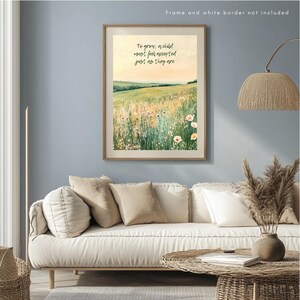 May include: A framed art print featuring a watercolor landscape with a field of wildflowers and the text "To grow, a child must feel accepted just as they are." The artwork is displayed above a white sofa with beige pillows, a woven coffee table, and a floor lamp.