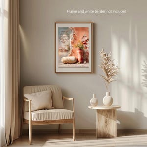 Pu&ograve; includere: Una stampa artistica incorniciata con una citazione e una natura morta con un vaso rosso con fiori, una pagnotta di pane e un muro usurato. La stampa &egrave; appesa sopra una sedia beige e un tavolino di legno.