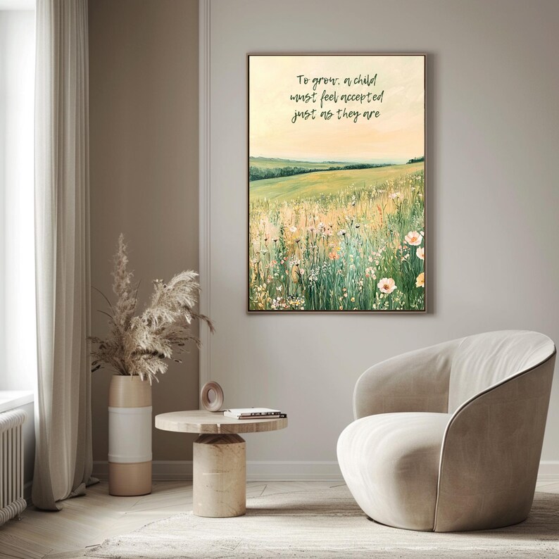 May include: A framed landscape painting depicts a field of wildflowers under a soft yellow sky. The artwork includes the text: "To grow, a child must feel accepted just as they are." The painting is displayed in a neutral-toned room with a modern chair and side table.