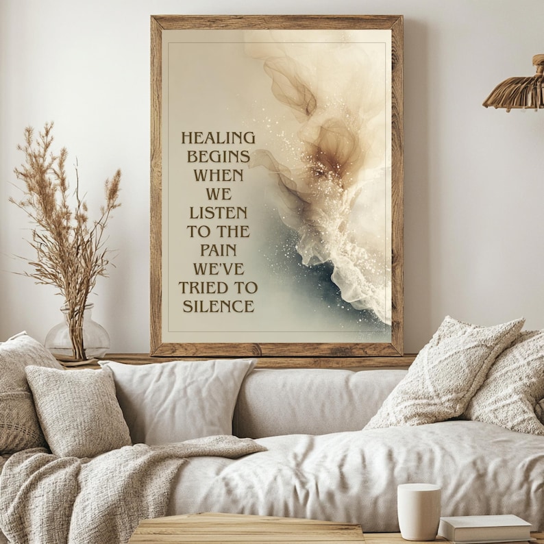 May include: A framed art print with a wooden frame. The artwork features abstract watercolor-style designs in beige, white, and blue hues. Text on the print reads: "HEALING BEGINS WHEN WE LISTEN TO THE PAIN WE'VE TRIED TO SILENCE."
