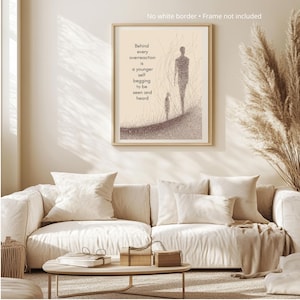 May include: A framed art print with a beige background and a minimalist illustration of two figures. The text reads, "Behind every overreaction is a younger self begging to be seen and heard." The artwork is displayed above a cream-colored sofa.