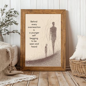 May include: A framed print with a light brown wooden frame. The artwork features two figures and the text: "Behind every overreaction is a younger self begging to be seen and heard." The figures are made of small dots.