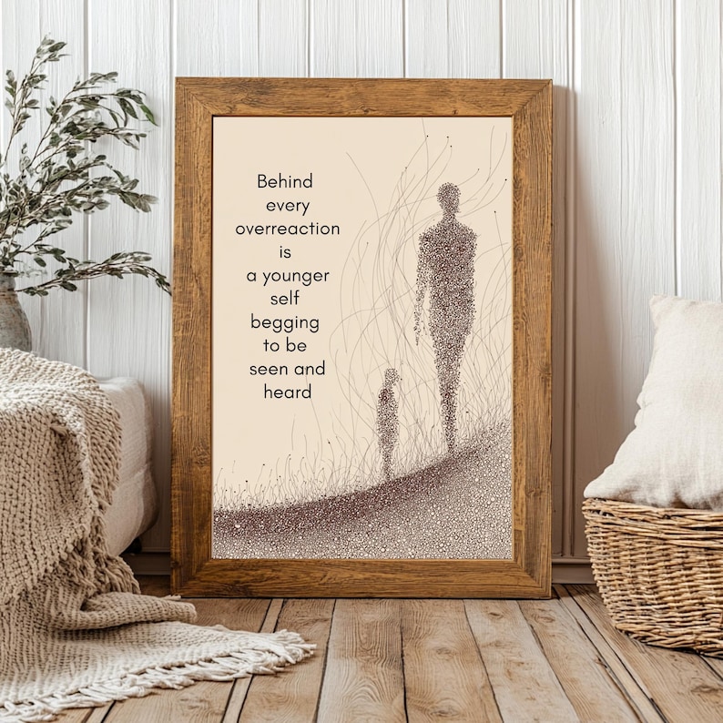 May include: A framed print with a light brown wooden frame. The artwork features two figures and the text: "Behind every overreaction is a younger self begging to be seen and heard." The figures are made of small dots.