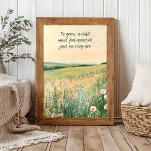 May include: A framed print featuring a pastoral landscape with a field of wildflowers and rolling hills under a soft, yellow sky. The print has a wooden frame and includes the text: "To grow, a child must feel accepted just as they are."