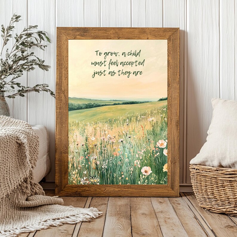 May include: A framed print featuring a pastoral landscape with a field of wildflowers and rolling hills under a soft, yellow sky. The print has a wooden frame and includes the text: "To grow, a child must feel accepted just as they are."