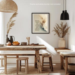 May include: A framed art print with the text "HEALING BEGINS WHEN WE LISTEN TO THE PAIN WE'VE TRIED TO SILENCE" hangs on a white wall. The room features a wooden table, stools, and a bench, with decorative vases and dried plants.