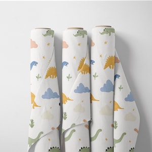 May include: Three rolls of white fabric with a repeating pattern of colorful dinosaurs, clouds, and stars. The dinosaurs are in shades of green, yellow, and blue. The clouds are peach and blue. The fabric is unrolled slightly.