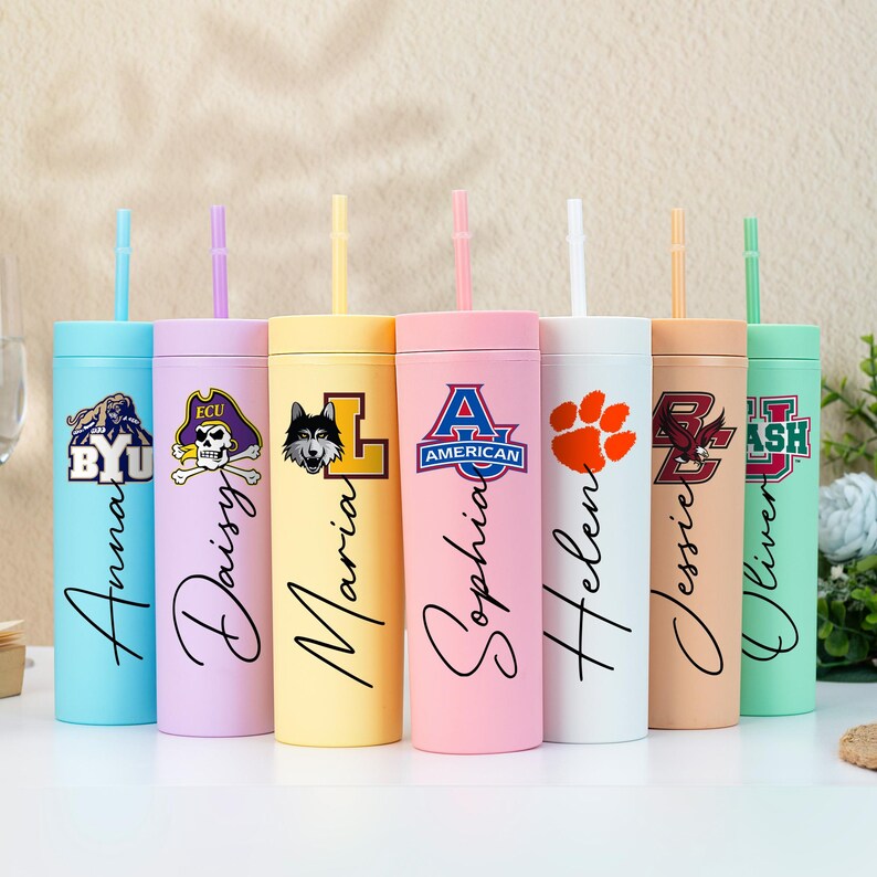 May include: A selection of pastel-coloured tumblers with straws, each personalised with a name in cursive script and a logo. The tumblers are designed for cold drinks. Each tumbler is a different colour, including blue, pink, and yellow.