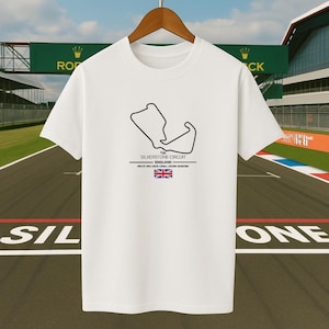 Könnte beinhalten: Weißes T-Shirt mit schwarzer Umrisszeichnung der Silverstone Circuit Rennstrecke in England. Der Text "SILVERSTONE CIRCUIT ENGLAND" ist darunter abgebildet, zusammen mit der Flagge des Vereinigten Königreichs.