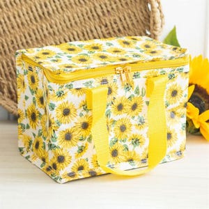 May include: A yellow and white lunch bag with a sunflower print and yellow handles. The bag has a zipper closure.