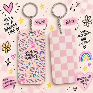 May include: A rectangular keyring with a silver metal ring and chain. The front features a pink background with colourful doodles and the text 'ELIZABETH'S BAD BITCH MANIFESTO' surrounded by various affirmations. The back has a pink and white checkerboard pattern.