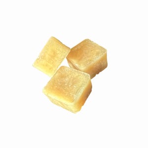 May include: Three translucent, light yellow cubes are arranged against a white background. The cubes have a slightly rough texture and appear to be made of a solid material. The lighting highlights the edges and surfaces of the cubes.