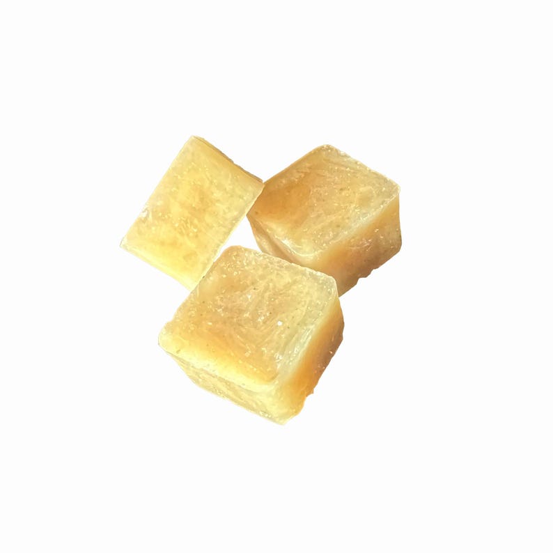 May include: Three translucent, light yellow cubes are arranged against a white background. The cubes have a slightly rough texture and appear to be made of a solid material. The lighting highlights the edges and surfaces of the cubes.