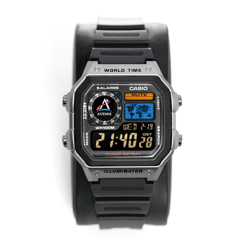 May include: A black Casio digital watch with a silver bezel. The watch face displays the time, date, and world map. The watch has the text "WORLD TIME", "CASIO", "ILLUMINATOR", and "10 YEAR BATTERY".