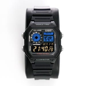 Pode incluir: Relógio digital Casio preto com mostrador quadrado e pulseira preta. O mostrador do relógio exibe a hora, a data e as funções de hora mundial. O relógio tem o texto "CASIO", "WORLD TIME" e "ILLUMINATOR".
