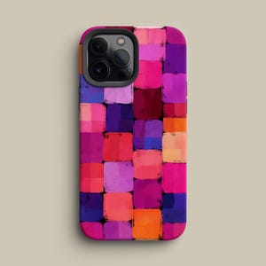 May include: A phone case with a colorful abstract design. The case features a pattern of squares in shades of pink, purple, red, orange, and blue. The phone case has a black camera module.