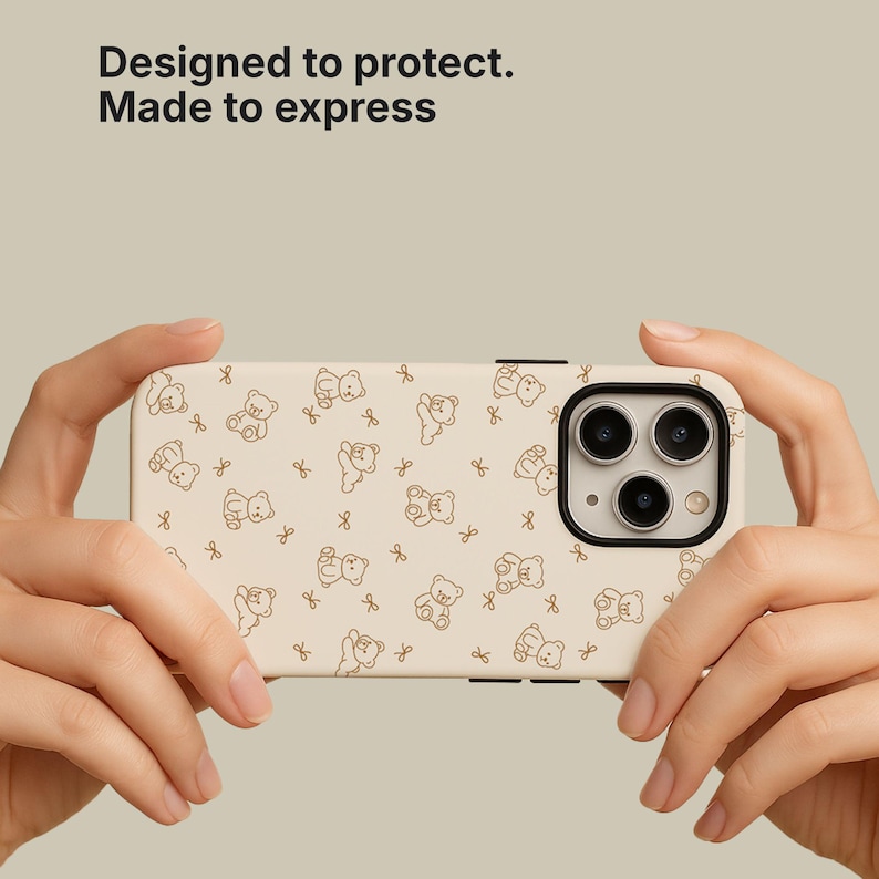 May include: A beige phone case with a repeating pattern of brown teddy bears and bows. The case has a black camera lens border and the text "Designed to protect. Made to express."