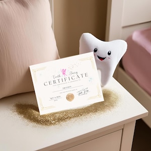 May include: A Tooth Fairy Certificate with gold accents and the name "Grayson" is displayed on a white surface. A plush tooth with a smiling face sits nearby. Gold glitter is scattered around the certificate.