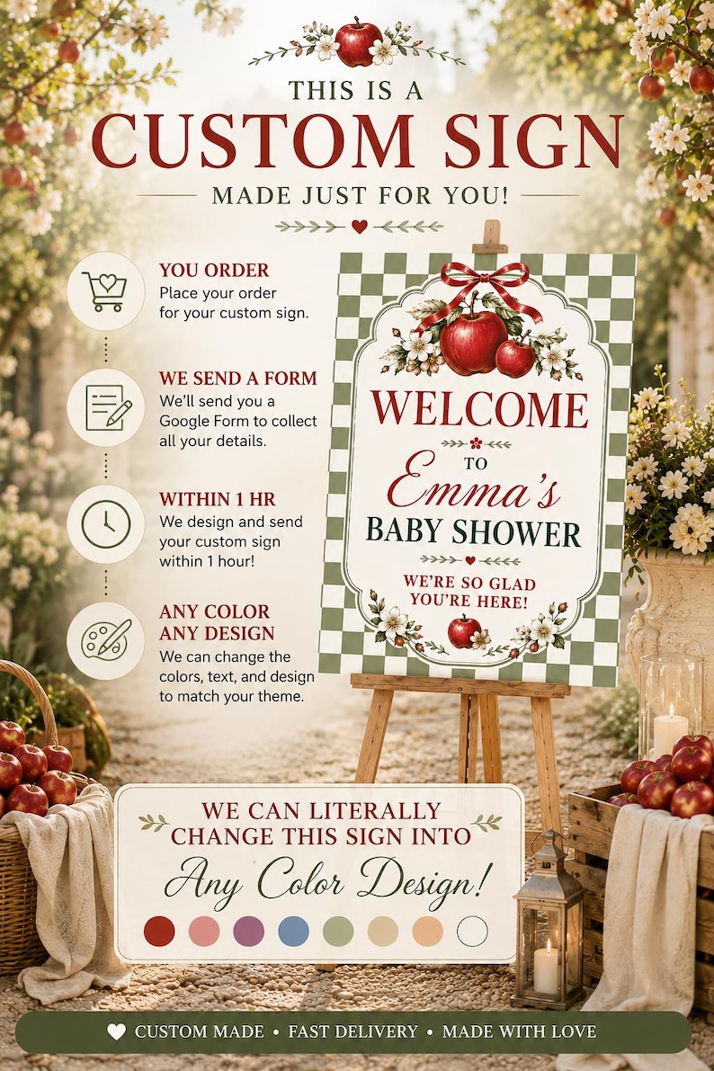 May include: A rectangular sign on a wooden easel featuring a green and white checkered border, red apples, white blossoms, and a red ribbon. The text reads: Welcome to Emma's Baby Shower, We're so glad you're here! The sign includes instructional text.