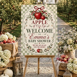 May include: A rectangular welcome sign for a baby shower featuring a light green and white checkered background. The sign displays the text APPLE of Our Eye WELCOME TO Emma's BABY SHOWER WE'RE SO GLAD YOU'RE HERE! with red apple and floral illustrations.