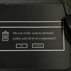 Pode incluir: Tapete de rato preto com um gráfico branco de uma janela pop-up. A janela exibe um ícone de lixeira e o texto: "Você realmente quer desinstalar a realidade e todos os seus componentes?" com os botões "OK" e "Cancelar". Um rato de computador preto está à direita.