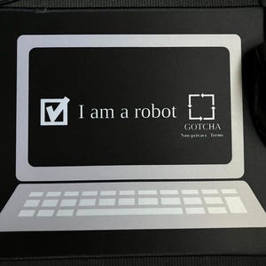 Op de afbeelding: Zwart rechthoekig muismat met een computerbeeldschermontwerp. Het scherm toont de tekst "I am a robot" met een vinkje en een vierkant met pijlen. Een zwarte computermuis bevindt zich rechts.