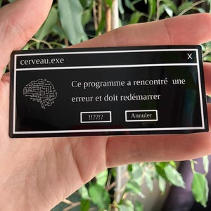 Peut inclure: Un rectangle noir avec le texte "cerveau.exe" et un message d'erreur simulé. Le message dit "Ce programme a rencontré une erreur et doit redémarrer." avec des boutons "!!??!?" et "Annuler".