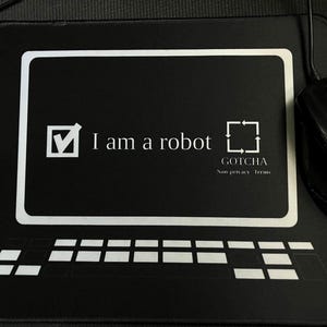 Puede incluir: Ratón y alfombrilla de ratón negros con el contorno blanco de una pantalla de ordenador y un teclado. La alfombrilla tiene el texto "I am a robot" con una marca de verificación y un cuadrado con flechas. También está presente el texto "GOTCHA Non privacy terms".