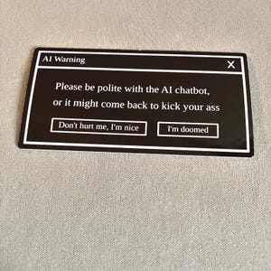 May include: A black rectangular sticker with white text that reads "AI Warning" at the top. The text below warns to be polite to the AI chatbot. Two buttons read "Don't hurt me, I'm nice" and "I'm doomed".