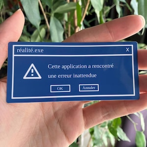 May include: A blue rectangle with white borders, resembling a computer error message. The text "réalité.exe" is at the top, and the message reads "Cette application a rencontré une erreur inattendue" with "OK" and "Annuler" buttons.