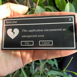 May include: A black rectangular sticker with a white border, designed to look like a computer error message. It features the text "love.exe", a broken heart icon, and the message "This application encountered an unexpected error." Buttons say "Cry" and "Cancel."