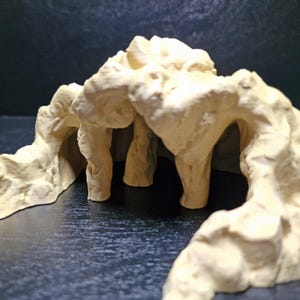 May include: A beige, cave-like structure with multiple archways and pillars. The textured surface suggests a rock formation, possibly for a reptile or aquarium habitat. The design features a naturalistic aesthetic.