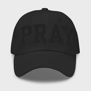 May include: Black baseball cap with the word "PRAY" embroidered across the front in a textured, tonal design. The cap has a curved brim and an adjustable strap at the back. The hat is made of a soft, durable fabric.