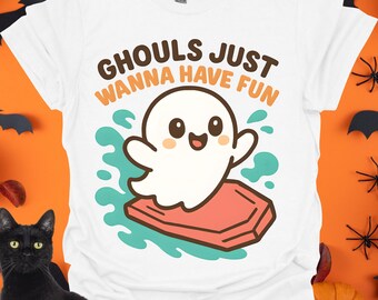 May include: White t-shirt with a Halloween-themed graphic. The design features a cartoon ghost with the text "Ghouls Just Wanna Have Fun" in brown and orange. The ghost is on a red platform with teal water splashes.