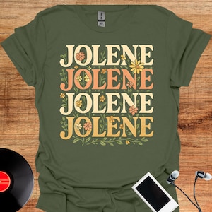 Könnte beinhalten: Ein olivgrünes Kurzarm-T-Shirt mit dem viermal untereinander gedruckten Wort JOLENE. Der Schriftzug ist in einer fetten, abgerundeten Schriftart mit einem Farbverlauf von Creme über Orange bis Gelb gehalten und mit kleinen Blumenmotiven verziert.