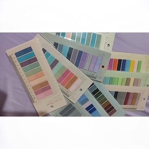 May include: A collection of color note sticky note pads. Each pad features a ruler edge and a series of rectangular sticky notes in various color palettes, including blues, greens, pinks, and oranges. The pads are arranged on a purple surface.