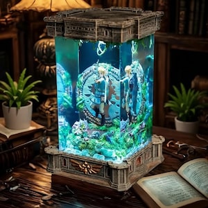 Puede incluir: Un diorama iluminado y detallado, inspirado en un videojuego, con una estructura en forma de castillo. La secci&oacute;n central transparente muestra personajes, mientras que la base y la parte superior est&aacute;n adornadas con elementos arquitect&oacute;nicos. El interior se ilumina con un brillo azul.