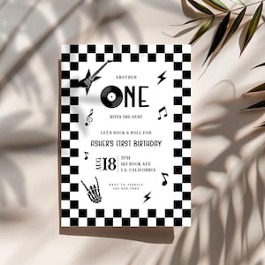 May include: Black and white rock and roll themed birthday invitation with a checkered border. The invitation includes a guitar, musical notes, and the text "Another One Bites the Dust" and "Asher's First Birthday".