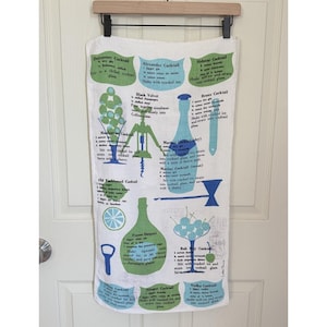 Puede incluir: Paño de cocina blanco con recetas de cócteles e ilustraciones en azul y verde. El diseño incluye imágenes de copas de cóctel, botellas y herramientas de bar. El paño presenta nombres de cócteles como "Sidecar Cocktail" y "Alexander Cocktail".