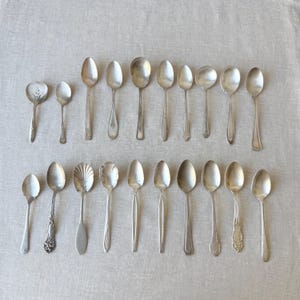 Cucharas de té vintage de plata surtidas, 20 piezas, diseños variados, cubiertos desiguales.