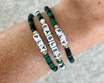 May include: Three bracelets with black and green beads and white letter beads spelling "FLY", "EAGLES", and "FLY".