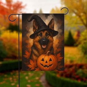 May include: A Halloween garden flag featuring a German Shepherd wearing a witch hat. The dog is positioned in front of a carved pumpkin and surrounded by autumn leaves. The flag is displayed on a black metal stand.