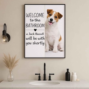 May include: A framed bathroom sign with a Jack Russell Terrier image. The sign reads "WELCOME to the BATHROOM" above a heart symbol and the text "a Jack Russell will be with you shortly". The dog is white with brown markings and is smiling.