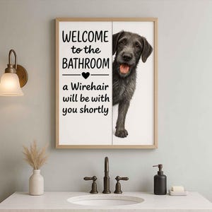 Op de afbeelding: Ingelijste badkamerbord met een illustratie van een Draadhaar hond. Het bord leest "WELCOME to the BATHROOM" boven een hartsymbool, gevolgd door "a Wirehair will be with you shortly" in zwarte tekst. De hond is grijs en kijkt achter het bord vandaan.