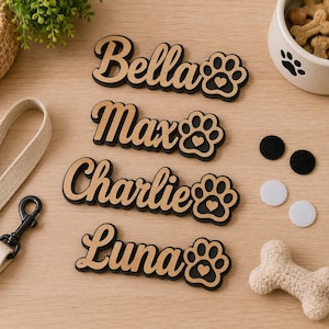Pu&ograve; includere: Quattro targhette in legno personalizzate con i nomi Bella, Max, Charlie e Luna in carattere corsivo. Ogni targhetta include un'icona a forma di zampa con un piccolo cuore ritagliato. Le targhette sono stratificate con legno chiaro e base nera.