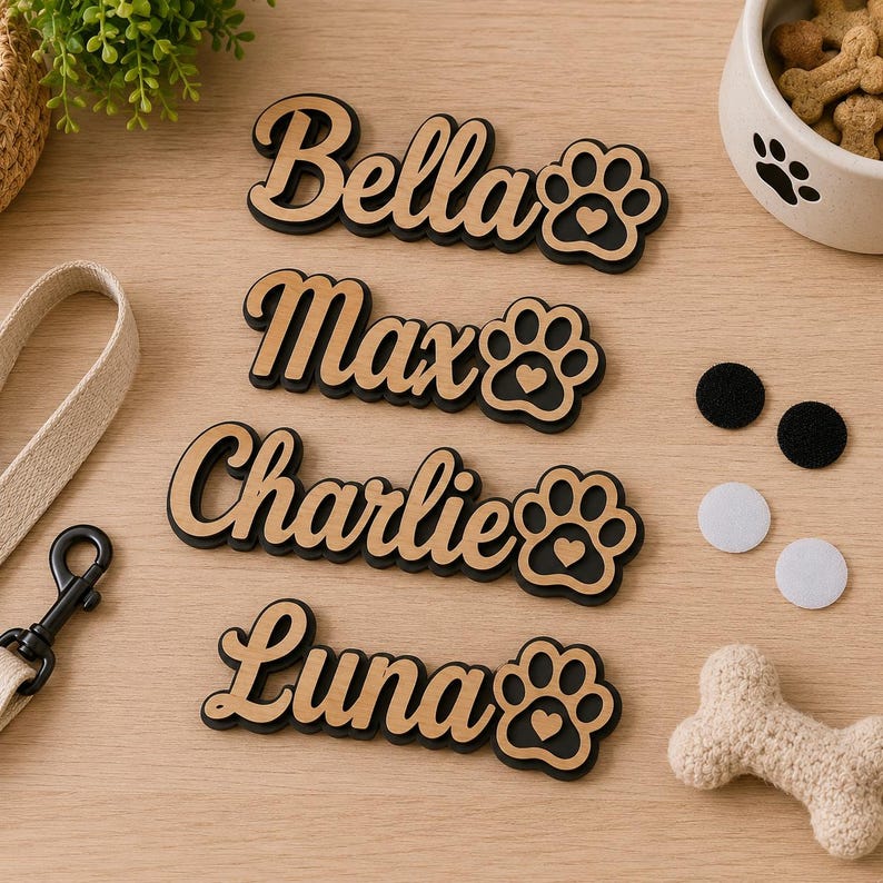 Pu&ograve; includere: Quattro targhette in legno personalizzate con i nomi Bella, Max, Charlie e Luna in carattere corsivo. Ogni targhetta include un'icona a forma di zampa con un piccolo cuore ritagliato. Le targhette sono stratificate con legno chiaro e base nera.
