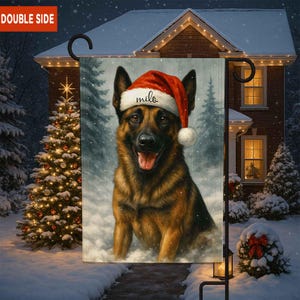 May include: A double-sided garden flag featuring a German Shepherd wearing a Santa hat with the name "milo" on it. The dog is in a snowy winter scene with a Christmas tree and a house in the background.