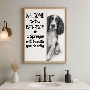 May include: Framed wall art featuring a black and white Springer Spaniel illustration. The artwork includes the text "WELCOME to the BATHROOM" and "a Springer will be with you shortly". The artwork is displayed above a bathroom sink.