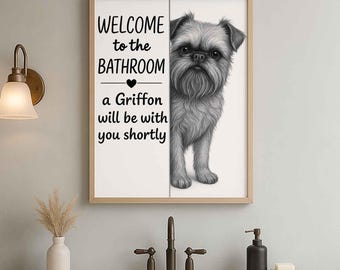 May include: Framed bathroom art featuring a grayscale illustration of a Brussels Griffon dog. The artwork includes the text "WELCOME to the BATHROOM" and "a Griffon will be with you shortly". The frame is a light wood color.